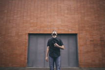 man standing in front of a brick warehouse looking up 