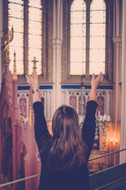 Woman with her arms raised in a cathedral.