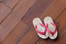 Child's flip flops on a wooden floor.