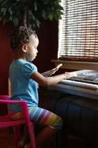 toddler girl playing a digital piano 