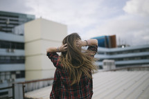 a teen girl on a roof grabbing her head 