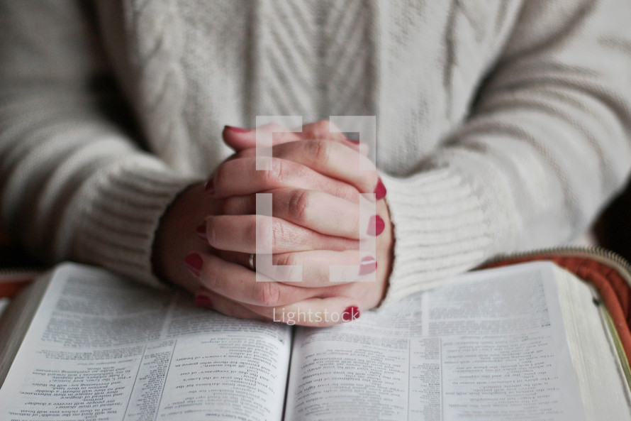 a woman praying over an opened Bible 