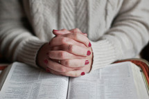 a woman praying over an opened Bible 