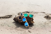sunglasses and driftwood on a beach 