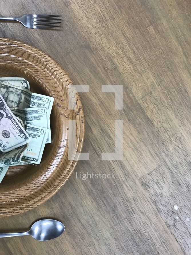 offering plate full of cash as a place setting 