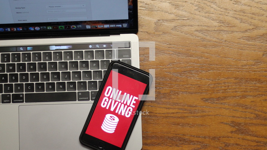 cellphone with an online giving app on the screen and a laptop 