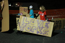 Teens holding cardboard "love" signs.