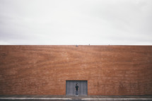 man standing in front of a brick warehouse building 