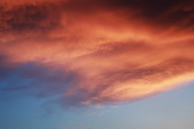 Dramatic sunset landscape with puffy clouds lit by orange setting sun and blue sky