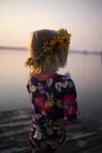 flowers in a girls hair while standing on a dock 