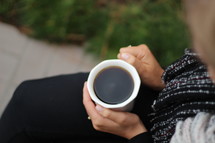a woman holding a mug of coffee in her lap 