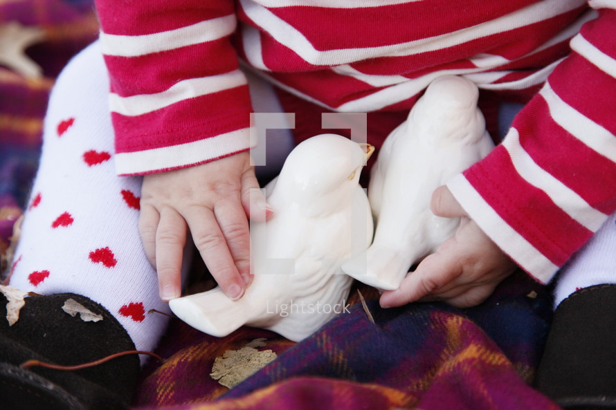 infant in heart tights playing with two white birds