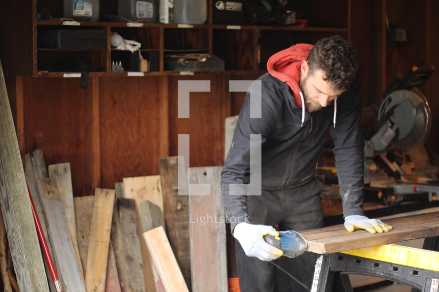 a man sanding wood in his workshop 