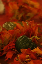 red and orange fall leaves and gourds on a Thanksgiving table