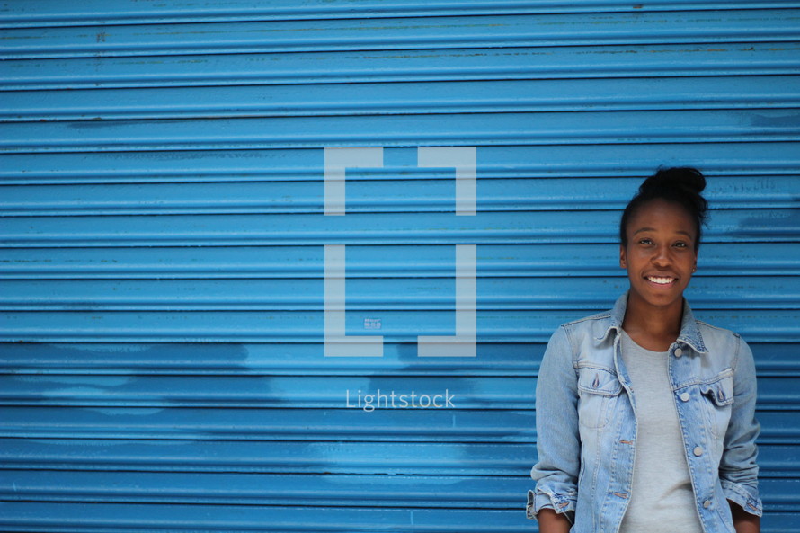 an African American woman standing in front of a blue wall 