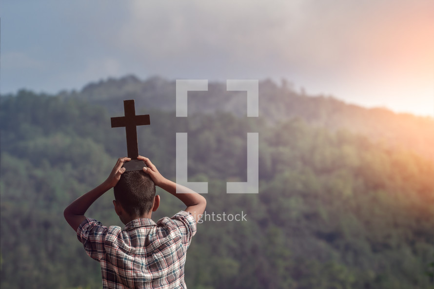 a boy holding a cross outdoors 