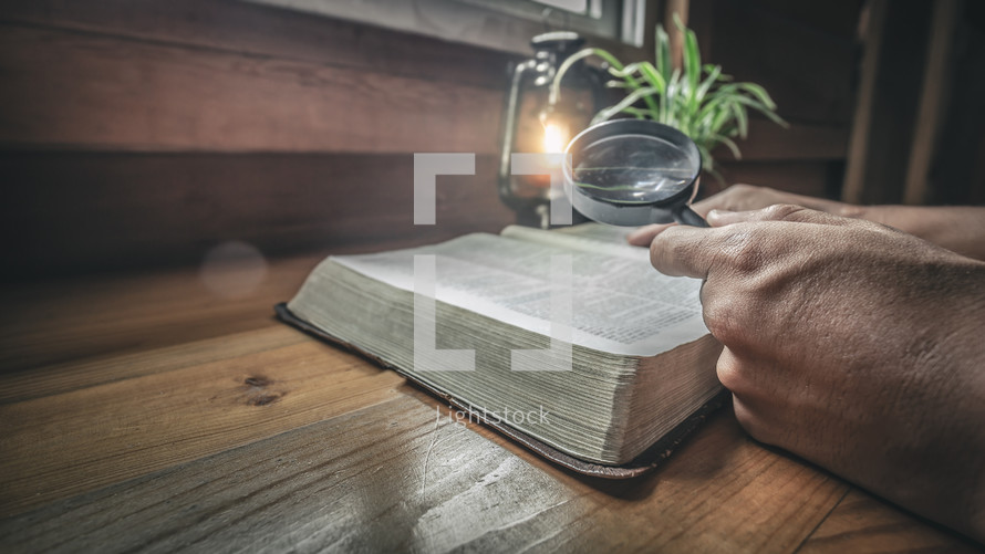 a person holding a magnifying glass reading a Bible 