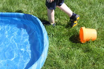 plastic pool in grass and toddler boy