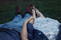 a couple lying in the grass holding hands 