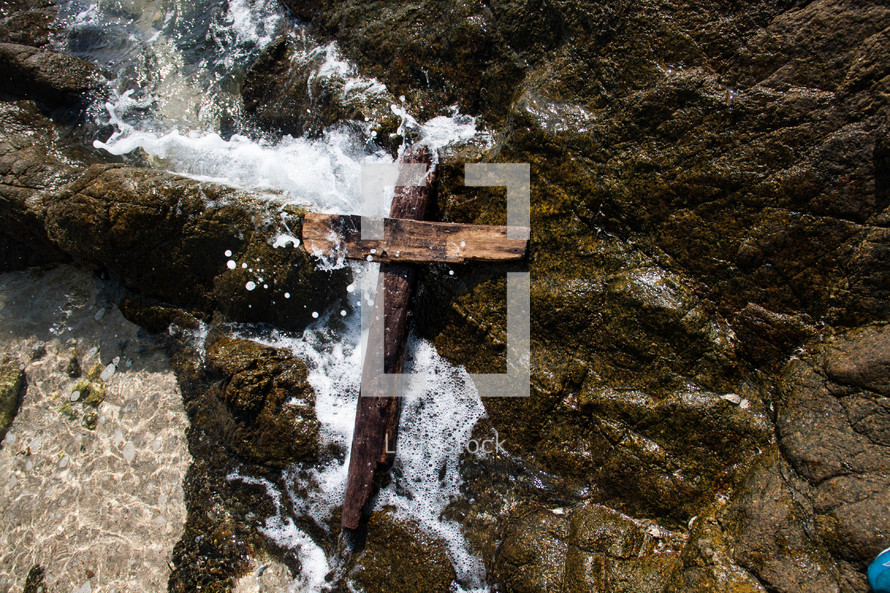 rugged cross on rocks and tide washing in 