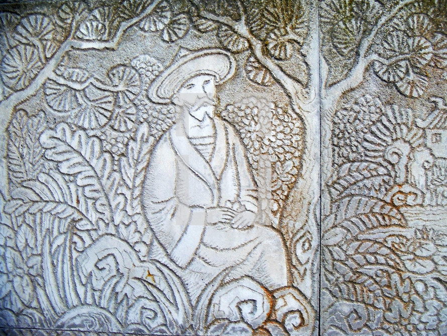 A carved relief of a peasant man sitting in a field with ferns, trees and vegetation. The peasant represents the world and the field represents the world where we are to go out and spread the gospel to all men. 