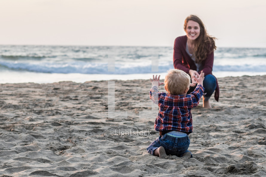 a toddler boy and mother on a beach 