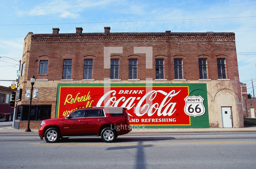 car driving down a small town downtown road and coca-cola sign 