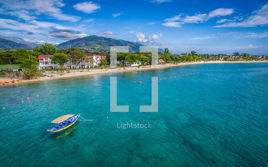 condos along a tropical beach shore and an anchored boat amongst the reefs 