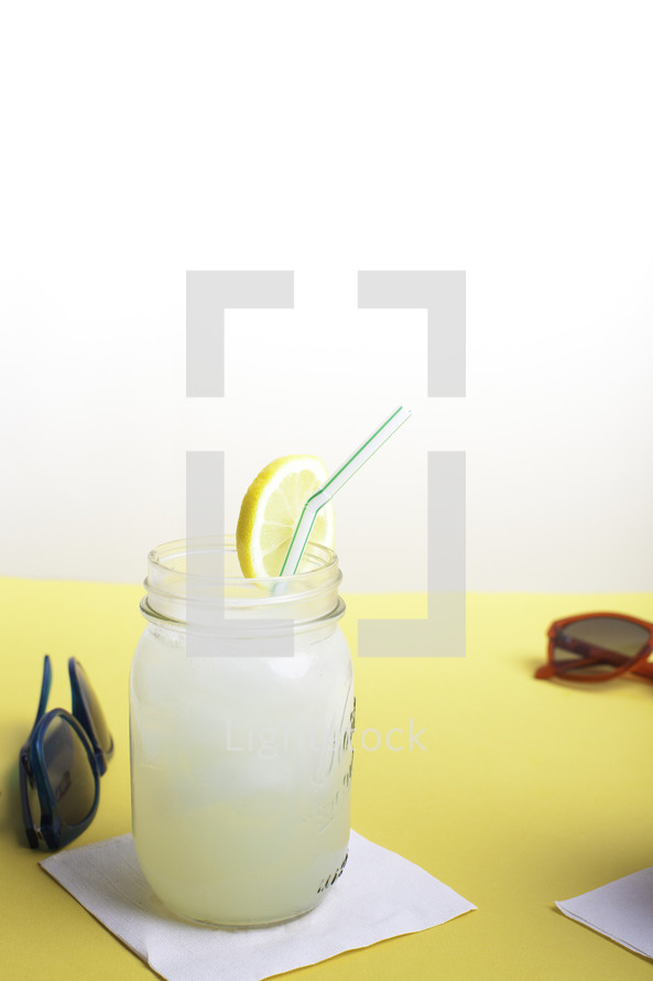 sunglasses and a mason jar of lemonade on a table 
