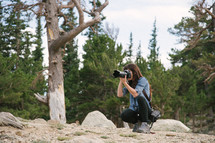 photographer with a camera taking a picture in a forest 