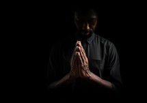 Black man praying on black background