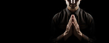 Praying man isolated on black background with copy space