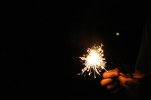 child holding a sparkler in the dark 