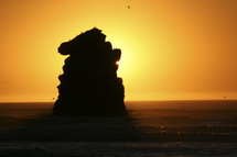 sun glowing behind  a rock
