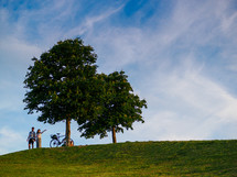a couple standing on top of a green hill 