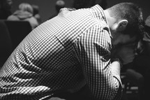 a man with his head bowed in prayer at church 
