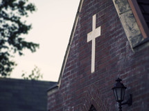A cross embedded in a brick church wall.