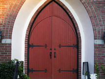 Large red doors in an arched brick entryway.