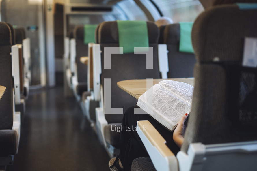 Girl reading her bible on en empty train. 