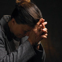 A woman with her head bowed in prayer.
