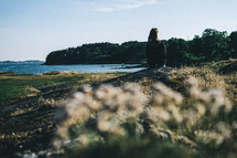 a woman sitting on a shore looking out at the water in Lysekil, Sweden