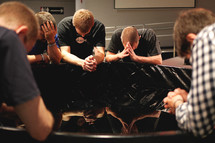 Young men sitting and praying together.