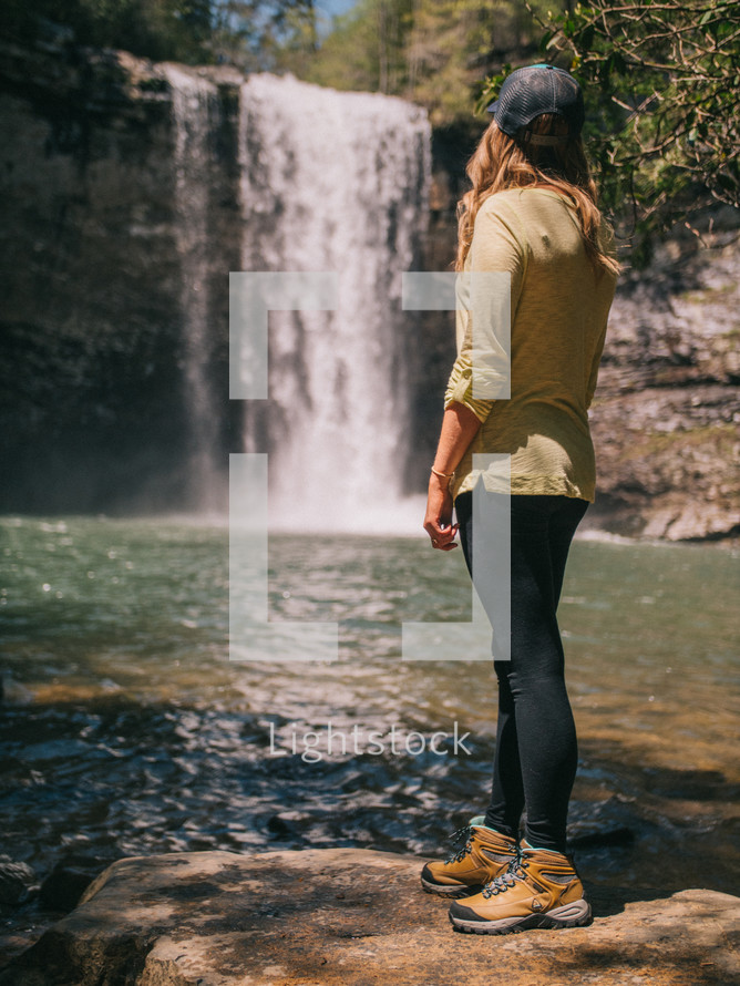 a woman standing in front of a waterfall 