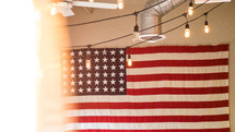 American flag hanging on a white and string of lights 
