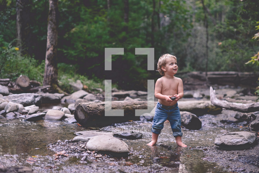 toddler boy playing in a stream 