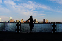 silhouette of a woman looking out at water 