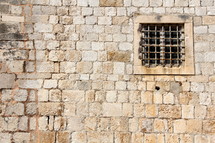 Barred window in ancient stone wall