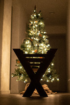 silhouette of a manger in front of a Christmas tree 
