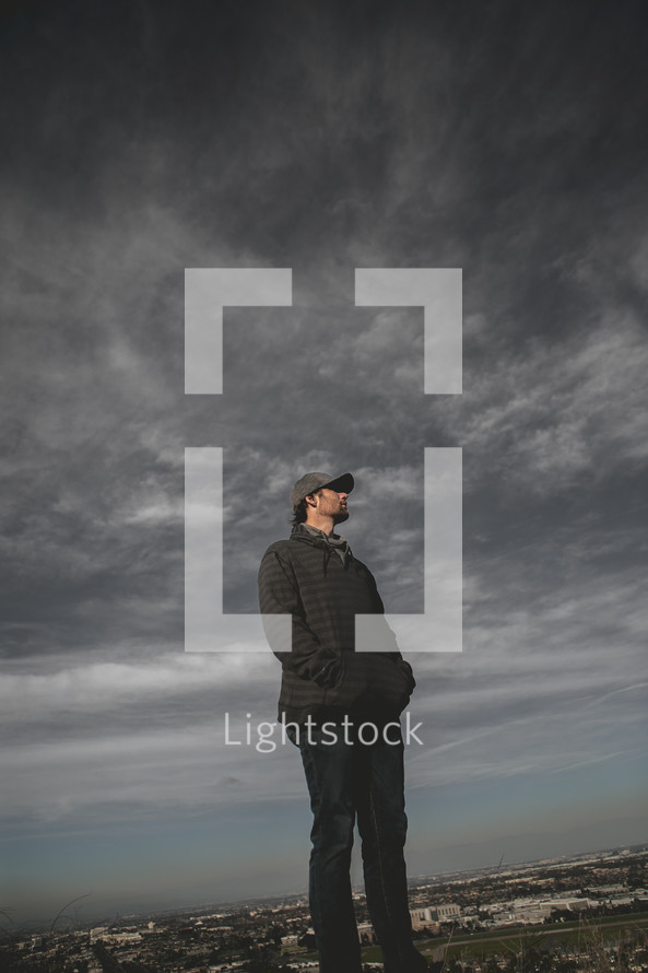 a man standing under a stormy sky 