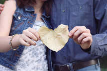 a couple holding a heart shape fall leaf 